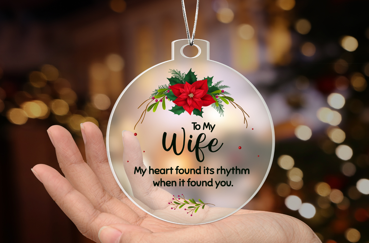 Hand holding romantic Christmas ornament for wife with red poinsettia and heartfelt message