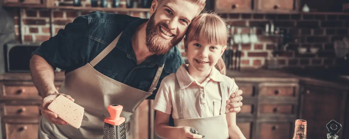 Father and young child in matching denim aprons smiling together while cooking