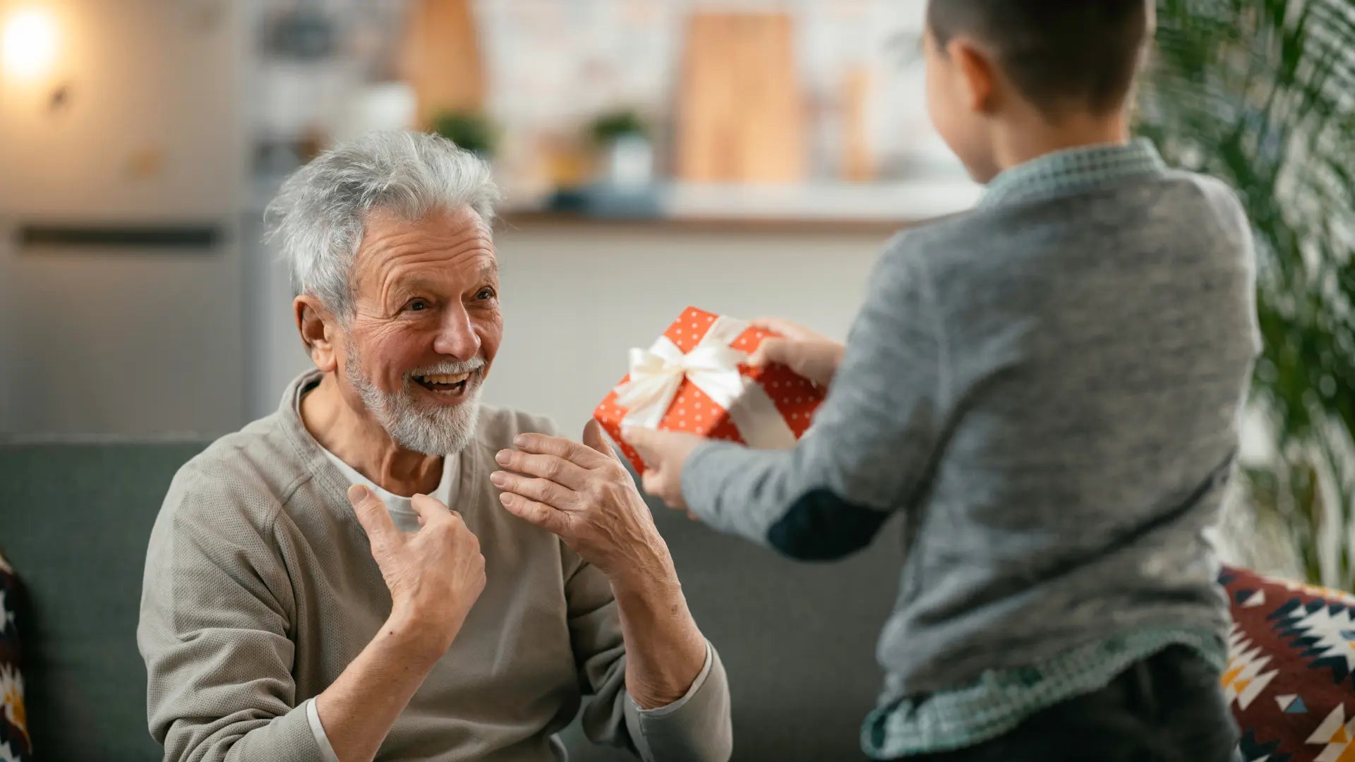 Retiring man receiving a wrapped gift from a young boy at his retirement celebration