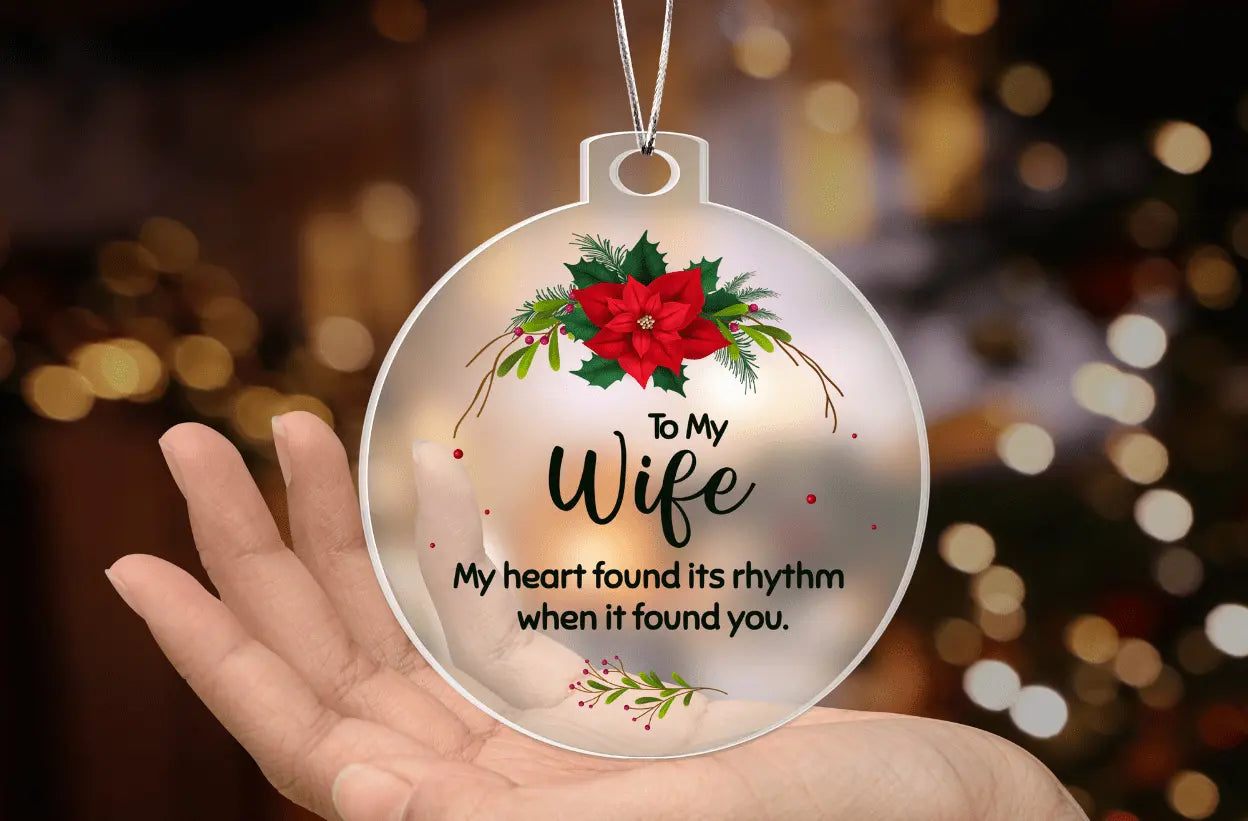 Hand holding a round christmas ornament engraved to my wife with a poinsettia design