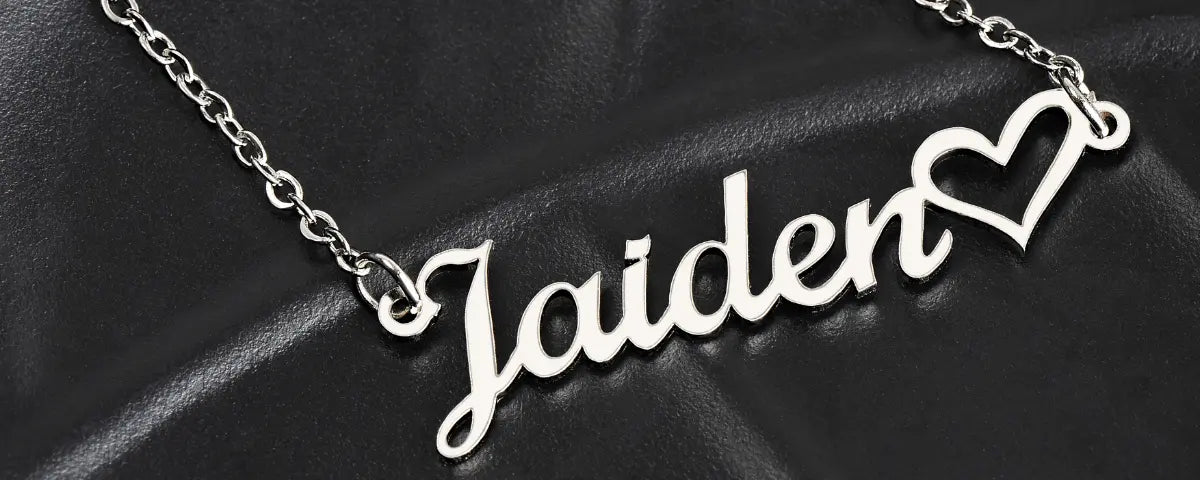 silver personalized name necklace reading jaiden with a heart charm, resting on black leather