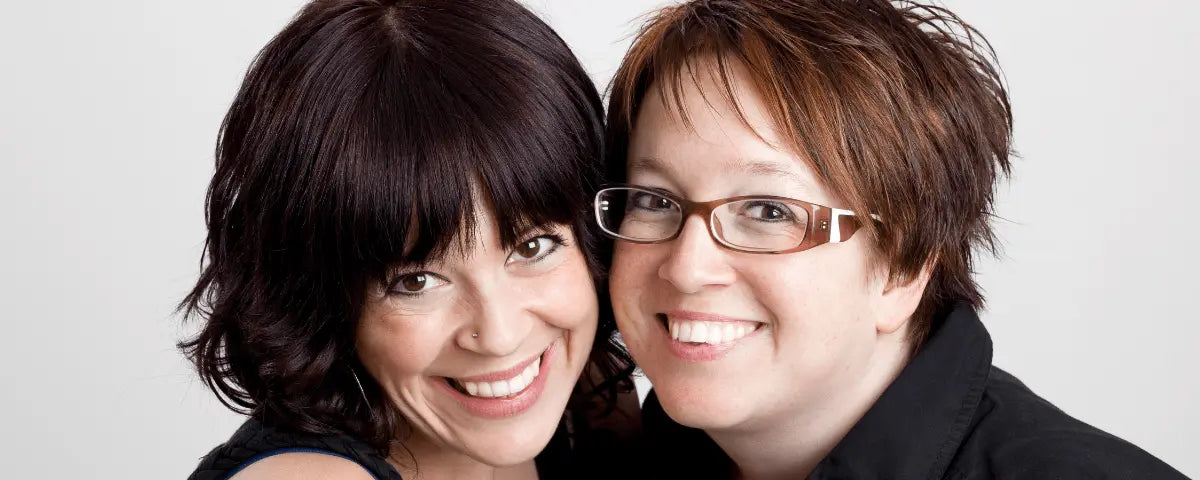 Two women embracing cheek to cheek and smiling, the bond of unbiological sisters