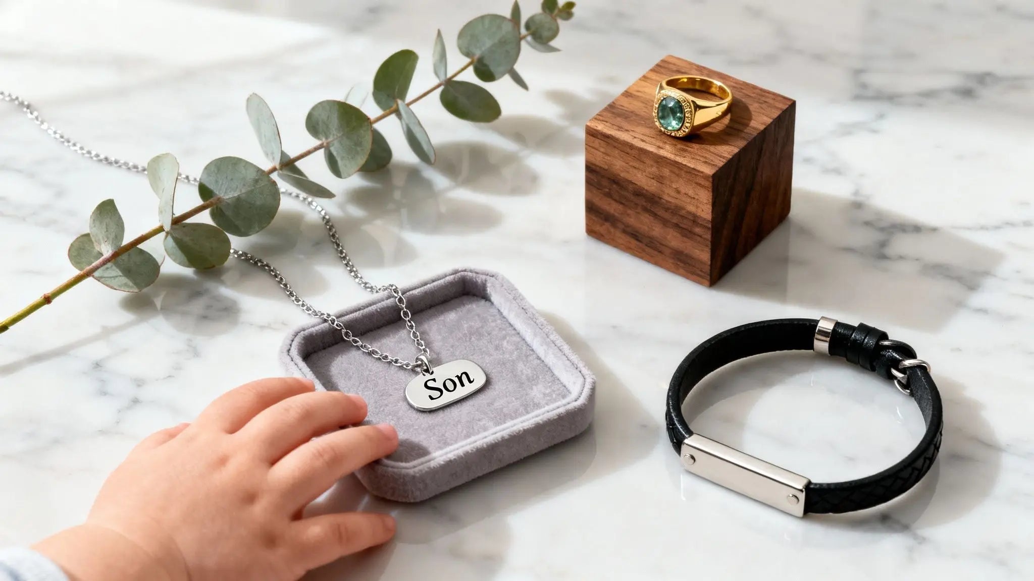 Engraved son dog tag necklace in a gift box beside a wooden keepsake box and leather bracelet